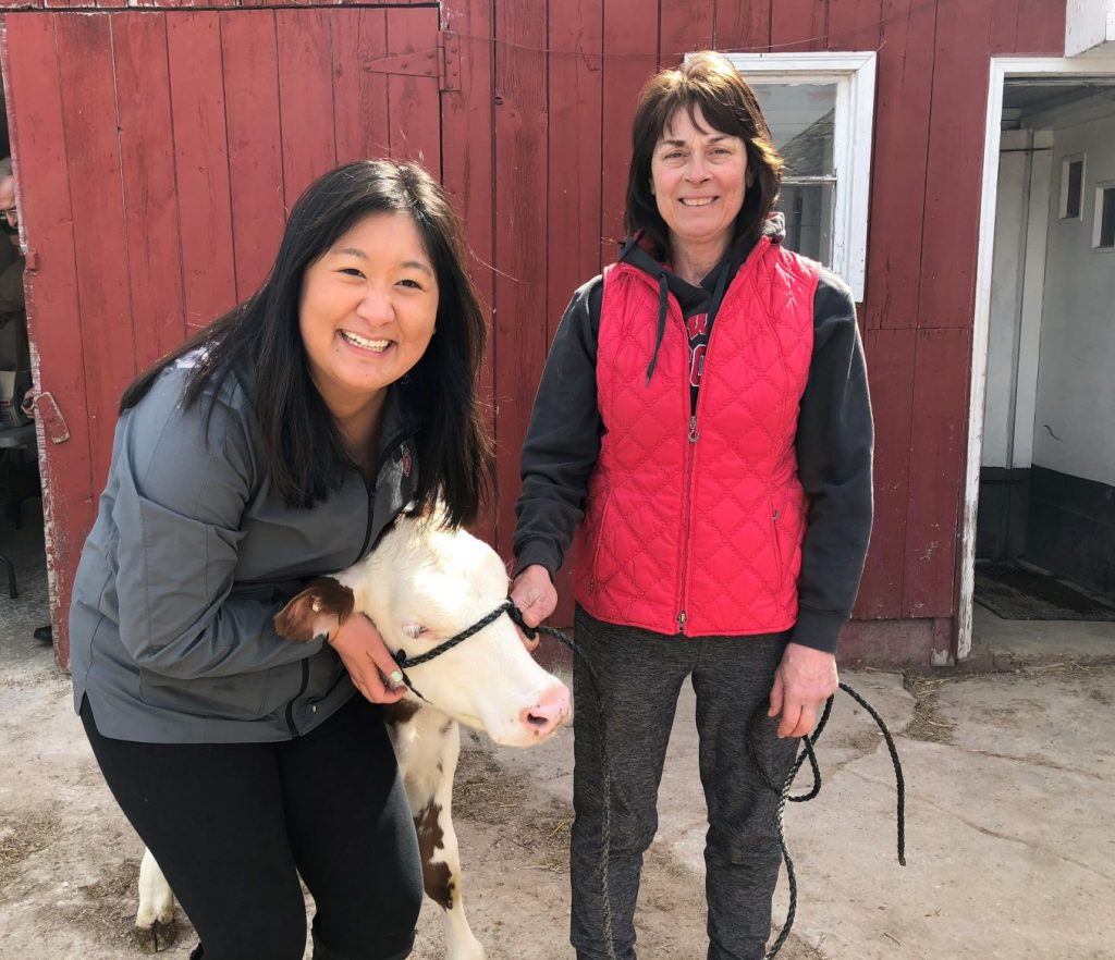 Two women smiling while posing with a cow