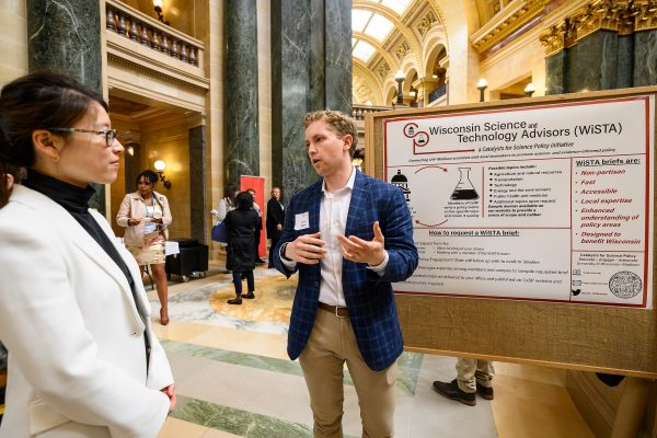 At right, Catalysts for Science Policy (CaSP) Co-President Chris Dade speaks with a member of the public during the Graduate Research Showcase held in the Wisconsin State Capitol rotunda during the UW–Madison's Day at the Capitol, a University of Wisconsin–Madison advocacy and outreach event held for legislators and staff on April 26, 2023. “As part of the Wisconsin Idea, that land grant mission, the work that we're doing on campus should be translated outside the boundaries of campus, not only to benefit citizens but inform policymaking,” noted Dade. “By organizing this event, we allow graduate students to bring some of that research and insight and maybe even new problems that policymakers haven't even thought a lot about, right here in the Capitol.” (Photo by Althea Dotzour / UW–Madison)
