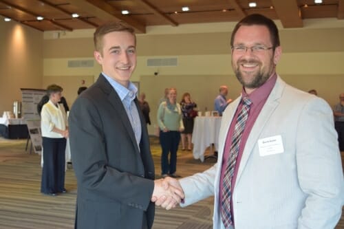 Two men smiling at the camera while shaking hands