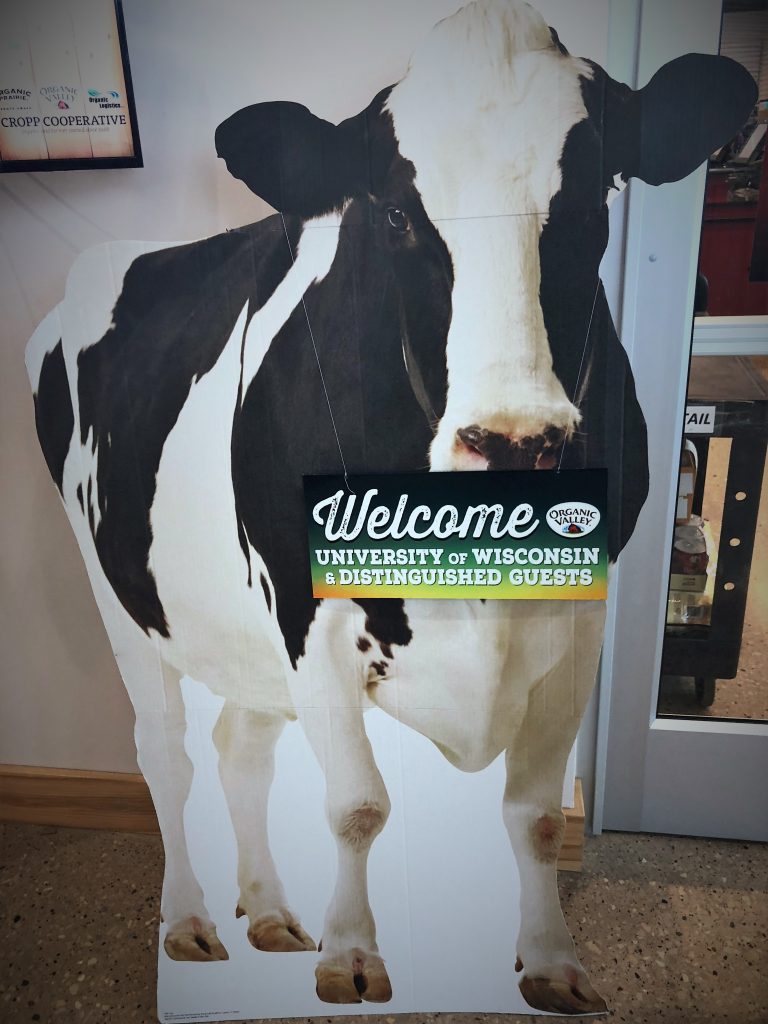Photo of a interior sign. Sign is of a black and white cow with a welcome sign for UW Madison visitors