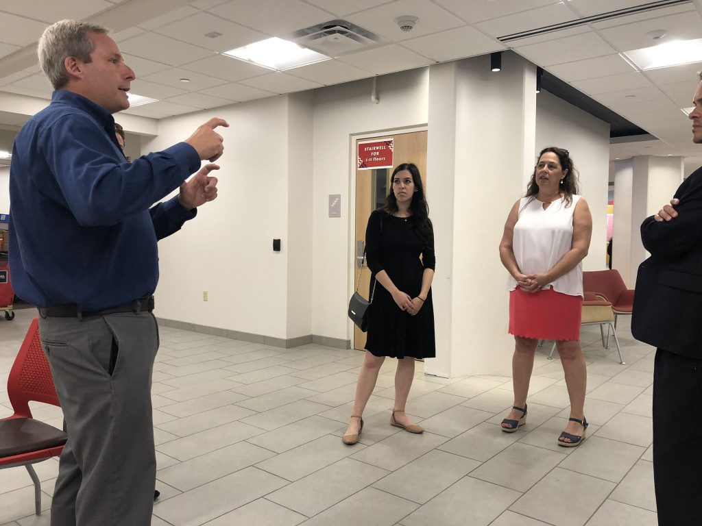 Four people standing listening to a man talk
