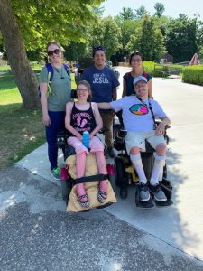 Group of people smiling at camera, two are seated in a wheel chair